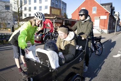 Klara Søndergaard fra Cyklistforbundet gør reklame for konkurrencen »Vi Cykler til Arbejde«. Bag styret er det Simon Gjesse, der har fuldt læs på ladcyklen. Han er cyklet fra Teglvænget og er på vej til dagplejen med Louie, som Camilla Gjesse passer på. Foto: Tom Laursen