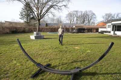 Mikkel Sørensen i sin baghave på Nørrevang 35 i Sunds. Her ville han opføre et dobbelthus til udlejning, fordi han ved, at der er mangel på udlejningsboliger i Sunds. Han fik nej fra Herning Kommune, men har siden vundet en klagesag hos Planklagenævnet. I baggrunden ses hustagene på to andre projekter med tæt-lav bebyggelse med udlejningsboliger, som Herning Kommune har tilladt. Foto: Tom Laursen