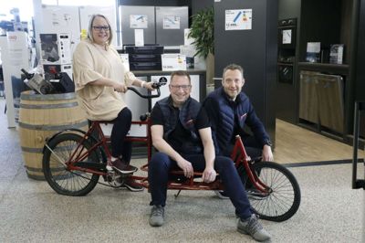 Den ikoniske røde cykel har altid været i butikken hos Skousen på Absalonsvej, og selv om ejerne har fået mange bud fra folk, som ville købe den, er den ikke til salg. Fra venstre: Lene Sindberg, Ole Nielsen og Jesper Isager. Foto: Henrik Ole Jensen