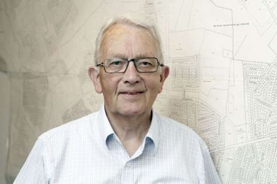 Bent Daniel Kristensen fotograferet i 2012, hvor det var 80 år siden, hans far, Svend Daniel Kristensen, slog sig ned i Herning som landinspektør. I baggrunden et matrikelkort, som blandt andet viser Rugvænget, hvor han selv boede med sin familie gennem knap fire årtier. Foto: Henrik Ole Jensen