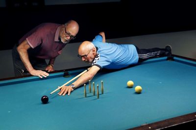 Peder Jensen (t.v.) fungerer ofte som instruktør i billard-klubben. Her er han for eksempel ved at fortælle Poul-Henning Mathiassen, hvordan han skal ramme de hvide baller ved hjælp af flere forskellige bander på bordet. Foto: Tom Laursen