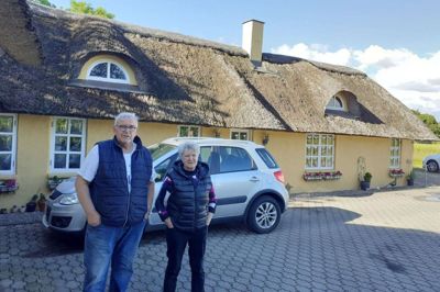 Ruth og John Christensen foran deres hjem gennem de seneste 26 år på Krogslundvej lidt vest for Snejbjerg. »Sådan er livet«, siger John Christensen ved udsigten til, at ægteparrets gennemrenoverede ejendom fra 1882 ligger i vejen for en ny 2+1-vej fra Herning til Ringkøbing. Foto: Jesper Wind