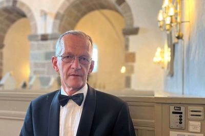 Finn Mundbjergs arbejdstøj er smoking og butterfly, og han sidder altid her tæt på teknikken lige inden for den store dør ind til Gjellerup Kirke, hvor den 66-årige kirketjener på søndag har sin sidste officielle arbejdsdag efter 31 år på posten. Foto: Jacob Hove