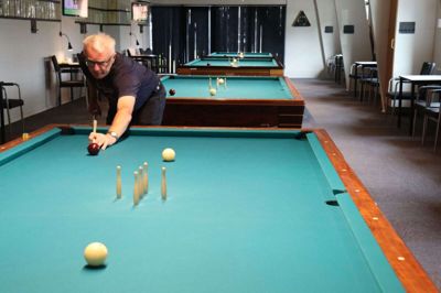 Godt nok er der sommerferie i Spjald Billardklub. Men regner det, er Sune Kirkegaard Olesen ofte at finde med kø, kegler og kridt. Foto: Mette Christensen