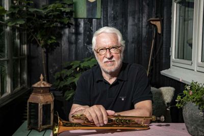 Sammen med hustruen Elsa bor Gerhard Ellerbæk i et gammelt og hyggeligt hus i Sydbyen i Silkeborg, hvor haven gror viltert og har flere små hyggekroge. Her er han fotograferet på verandaen lige ved indgangen til huset. Når han skal øve sig, går han ind i stuen og sætter en cd på, som han spiller til. Og det synes hustruen også er hyggeligt. Selvom Gerhard Ellerbæk har spillet i så mange år, mener han, at han fortsat kan udvikle sig og blive bedre. Samtidig er det vigtigt, at læberne hele tiden holdes i træning, når man spiller et instrument som trompet. Foto: Martin Ballund