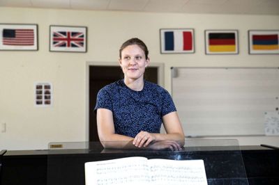 Den nye dirigent for Midtvest Pigekor, Frieda Funk, i pigekorets øvelokale. På væggen ses flag fra de nationer, som koret har besøgt - snart er det tid for et genbesøg i USA. Foto: Tom Laursen