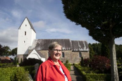 Marianne Lis foran Vinding Kirke, hvor hun efter 23 år er stoppet som kirkesanger. - Jeg har altid elsket at komme i kirke og synge. Musikken kan nå ind til sjælen, fortæller hun. Foto: Tom Laursen