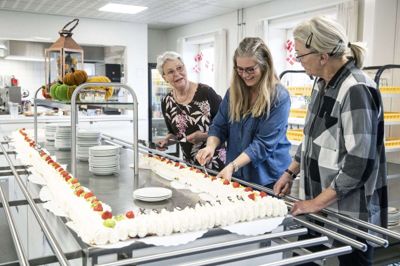 Så er der kage til folket. Lisbeth Kirkegaard (t.v.), der er frivillig og formand for centerrådet på Koloritten, og i midten aktivitetskoordinator Lisbeth Wium-Andersen skærer for til en af gæsterne ved markeringen af Kolorittens 30-årsjubilæum. Foto: Malene Tswa