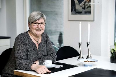 Anna Marie Serup Jensen på sin yndlingsplads i lejligheden i »Ørstedgården«. Hun kunne selv vælge farve til HTH-køkkenet bag hende. Og opvaskemaskinen kom med som en ny ting med renoveringen. Så slipper hendes gæster for at hjælpe med opvasken, fortæller hun. Foto: Chresten Bergh
