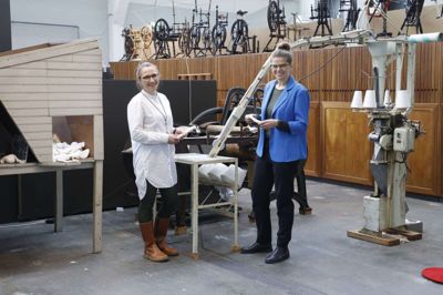 Undervisningsansvarlig Katrine Lewinsky Moestrup og Tekstilmuseets direktør, Kristine Holm-Jensen, står her ved den maskine fra 1950-1960’erne, der fremstillede engangsbind. Her er både en maskine, som stanser fyldet ud - det består af cellulose, som er et træprodukt - og en maskine, som fylder fyldet inden i et gazebindsagtigt hylster. Tekstilmuseet har fremstillet et kit, man kan købe, så man kan strikke sit eget hygiejnebind. Det gjorde deltagerne ved et arrangement på museet for nylig også. Katrine Lewinsky Moestrup fortalte bindets historie og demonstrerede maskinen, der fremstiller bind, og så gik de i cafeen og strikkede og snakkede. Næste guidede tur og strikkecafé holdes torsdag 11. maj. Foto: Henrik Ole Jensen