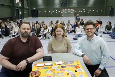 Elex Niels Kristensen (t.v.), Katrine Harbo Voller og Kasper Ladekjær poserer foran det brætspil, der skulle teste elevernes økonomiske evner. Foto: Henrik Ole Jensen