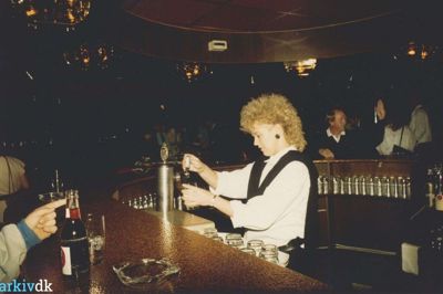En servitrice er i fuld gang med at skænke øl på Romantica. De kunne noget med håret dengang, tydeligvis. Foto: Lokalhistorisk arkiv