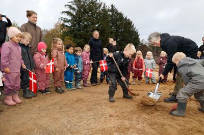 Oscar Kjær Vejlin i sort regntøj og Jonas Vinther Jensen hjalp udvalgsformand Anne-Mette Bang Rasmussen (V) med det første spadestik til Linds nye daginstitution.