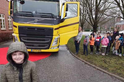 Kasper Sønderborg skulle gå ud foran lastbilen »Bumle«, indtil hans skolekammerater oppe i førerhuset kunne se ham. Charlotte Madsen ved fordøren sørgede for at alle børnene fik skoene af, inden de kom ind i førerhuset med lædergulv.