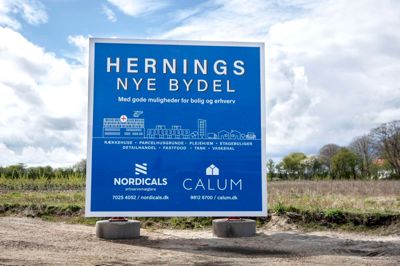Det store skilt blev stillet op i 2021 med løfter om butik, tank, fastfood-restaurant, plejehjem og hundredvis af boliger, men der er stadig ikke gået en spade i jorden på markerne syd for sygehuset i Gødstrup. Foto: Tom Laursen