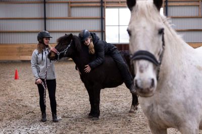 Det er samværet med hesten, der er i fokus i Helene Hviids coaching med heste. Her viser hendes datter, 14-årige Kate, hvordan nogle af klienterne holder af at ligge ned over hestens hals for at få en mere kropslig fornemmelse af hesten og sig selv.