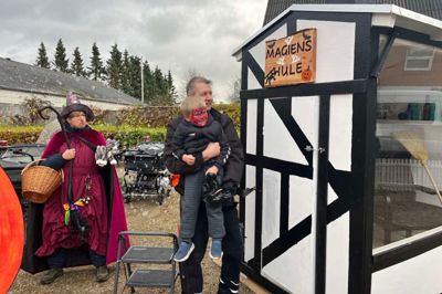 Kenneth Rasmussen har bygget huset, der torsdag formiddag fik navnet »Magiens Hule«. Han fik hjælp til navneafsløringen af Laurids, der går i Børnehaven Himmelblå. Bag makkerparret ses den venlige heks Karen.