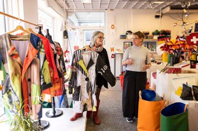 Underviser Karen Schelde (t.v.) og forstander Anna-Mette Bonde i butikken, der hører til det arbejdende værksted »Fokus på talent«. Her kan man købe kurve, flag, frakker, tasker, pynt ... ja, en masse produkter - alt sammen produceret af rest- og overskudsmaterialer.