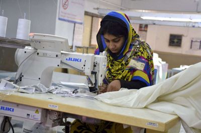 En pakistansk arbejder syer tekstiler på en fabrik i Faisalabad, hvor dansk milliardlån nu skal rense spildevandet fra fabrikkerne. (Arkivfoto).