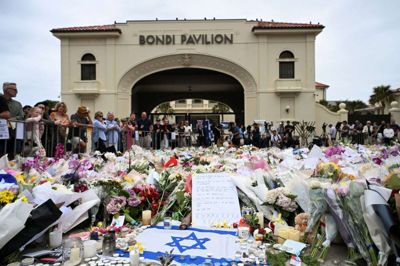 Et israelsk flag ligger foran bunker af blomster ved Bondi Beach. Søndag blev et jødisk Hanukkah-arrangement angrebet af to bevæbnede mænd.