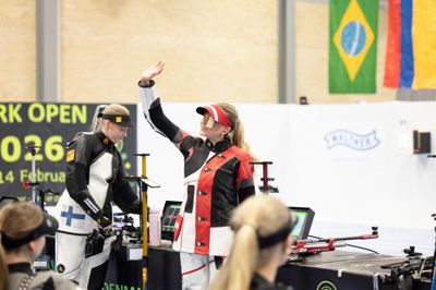 Rikke Mæng Ibsen vinker ud til publikum efter fredagens guldmedalje ved Denmark Open Air i Vildbjerg. Imens sætter finske Viivi Kemppi skuffet geværet fra sig. Finnen kom ind til finalen som vinder af den indledende skydning, hvor hun satte ny finsk rekord med 633,5 point på 60 skud.