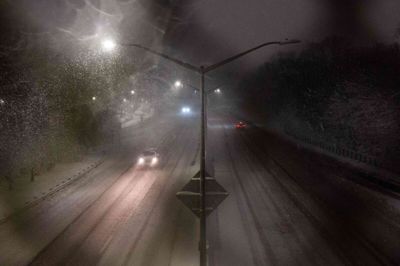 Få biler kører på en motorvej, mens sne begynder at falde natten til mandag dansk tid i bydelen Brooklyn i New York. Myndighederne fraråder alle unødvendige rejser på grund af en kraftig snestorm.