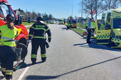 Ambulancen til højre blev svært beskadiget ved sammenstødet på Vesterholmvej. I baggrunden ses den væltede personbil, som ambulancen ramte med høj fart.