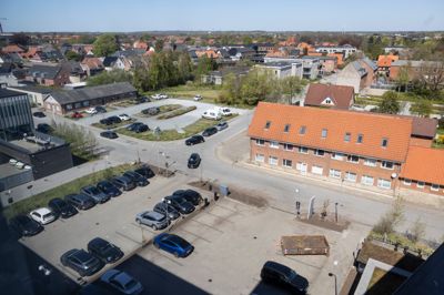 Trafikken i Haraldsgade-kvarteret er i forvejen belastet, og snart kommer der flere biler i området. En ny lokalplan baner vej for et kontorhusbyggeri, som skal opføres mellem politistationen og Dronningens Boulevard. Samtidig skal den lille p-plads øverst i billedet erstattes af et p-hus, så der sikres nok p-pladser i området. Det har fået politiet til at frygte for, at udrykning fra politistationen (til venstre) kan blive vanskeliggjort. Flere af naboerne i kvarteret er heller ikke vilde med udsigten til endnu flere biler.