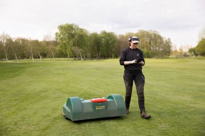 Greenkeeper Anne Frost inspicerer robotplæneklipperen, der arbejder på Herning Golf Klubs hul 8. Hun kan styre robotten via en app på sin telefon.