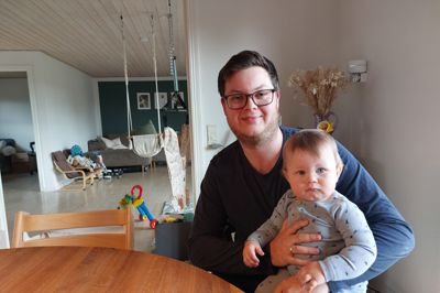 Emil Silcowitz-Hansen med Birk, snart et år, i favnen hjemme i Sinding. Emil Silcowitz-Hansen er formand for den nye forening, der skal ansætte en fællesskabsbygger i sognet under projektet »Det kræver en landsby«. Sinding er, siger han, et godt område at bo i, men der er altid plads til forbedring.