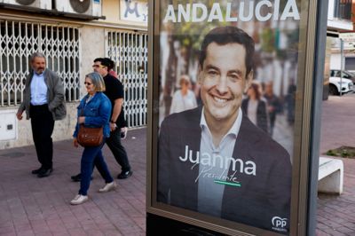 Folk går forbi en plakat af Juanma Moreno Bonilla - den regionale politiske leder og kandidat for det konservative parti, PP - søndag under valg i den sydspanske region Andalusien.