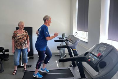 70-årige Inger Mikkelsen giver den gas på det nye løbebånd, der netop er installeret i et af motionslokalerne i Multihuset Den Gamle Skole i Klovborg. Jonna Rehde, formand for aktivitetsrådet på Bavnehøj, har været med til at skaffe pengene til løbebåndet og flere andre motionsmaskiner.