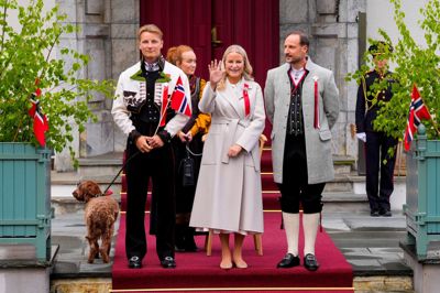 Kronprinsesse Mette-Marit, kronprins Haakon og prins Sverre Magnus ser et optog og vinker på Norges nationaldag. På billedet har Mette-Marit et næsekateter på. Det fører ilt til luftvejene hos kronprinsessen og hjælper med lettere at trække vejret.
