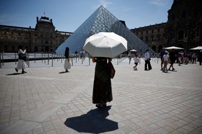 En person beskytter sig mod solen foran det verdensberømte kunstmuseum Louvre i Paris under hedebølge sent i maj i Frankrig.