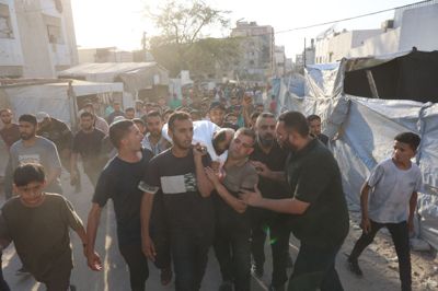 Palæstinensere bærer liget af en person, der er blevet dræbt i en israelsk angreb på en teltlejr.