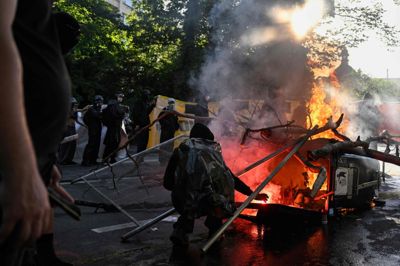 En demonstrant står ved en brændende skraldespand i Genève under demonstration mod G7-møde søndag.