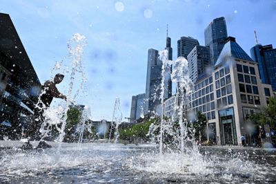 En mand køler sig ned i et springvand i Frankfurt am Main fredag.