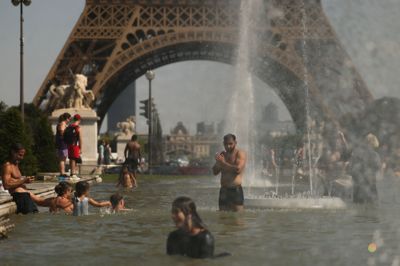 Folk køler sig ned i et springvand foran Eiffeltårnet i Paris tidligere på ugen.