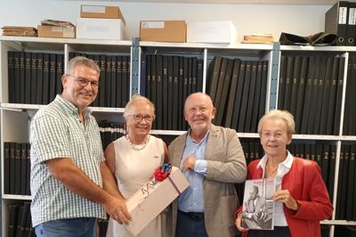 Rammen omkring fortællingen om Volmer Lind var den bedst tænkelige. Ikast Lokalhistoriske Arkiv ligger nemlig i de lokaler, hvor Volmer Lind Trikotagefabrik i sin tid havde til huse, og som Ikast Kommune købte i 1980. Foran væggen med de indbundne årgange af Ikast Avis ses her Volmer Linds børn fra venstre Strit Doris, Mikkel og Trine, der fremviser den nye bog. Familien havde medbragt en særlig gave fra Liechtenstein til Carsten Jensen, nemlig en flaske udsøgte bobler fra en lokal vingård.