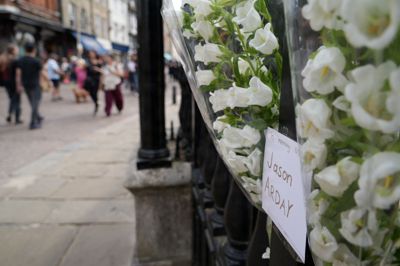 Folk går i Cambridge forbi blomster, der er sat op til minde om Jason Arday.