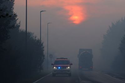 Brandbiler og en lastbil med en vandtank ses søndag køre gennem røg under en naturbrand i Hautes Fagnes-regionen i Belgien.