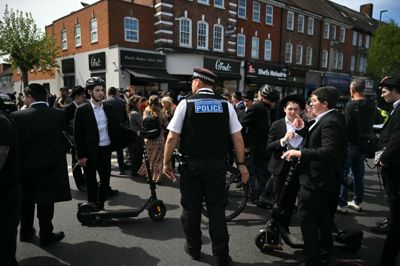 Politibetjente beder yngre medlemmer af det jødiske mindretal om at flytte sig fra et afspærret område i London-bydelen Golders Green 29. april, efter at to jødiske mænd var blevet stukket ned med kniv. Den mand, som blev anholdt i samme ombæring, nægter sig fredag skyldig i dobbelt drabsforsøg.