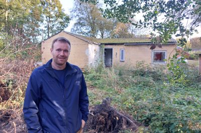 Jeppe Væggemose, formand for Foreningen Abildå Forsamlingshus, foran den tidligere kulbarak, der nu bliver væltet med støtte fra Herning Kommune. Den 800 kvadratmeter store grund er ryddet med hjælp fra byens frivillige og skal blive til et nyt opholdssted for byen og for forsamlingshusets mange gæster.