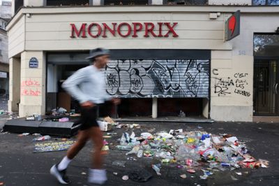 En person løber forbi en hærget butik i Paris dagen efter demonstrationer. Billedet er taget den 18. oktober.