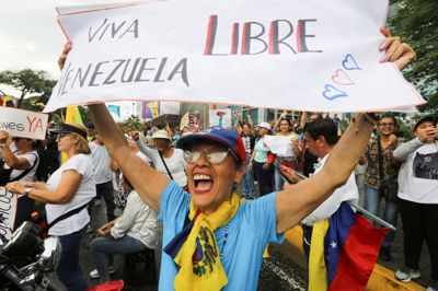 »Længe leve et frit Venezuela« står der på et skilt, som en demonstrant holder op under en demonstration i byen Valencia i Venezuela torsdag.