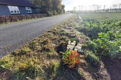 Fredag morgen var der lagt blomster og tændt lys ved ulykkesstedet på Ørrevej syd for Aulum, hvor en 19-årig kvinde mistede livet torsdag. I baggrunden ses huset, hvor Anette Revsgaard Sejbjerg og hendes mand boede i 21 år, og svinget, som parret flere gange gjorde opmærksom på deres bekymring for.
