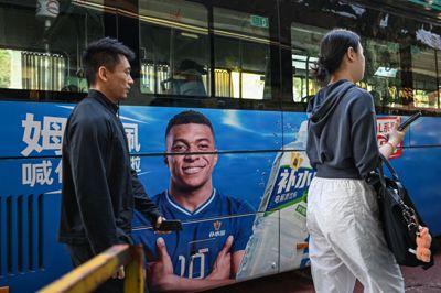 En bus kører tirsdag rundt i kinesiske Shanghai med en reklame for en energidrik med den franske fodboldspiller Kylian Mbappé. Et typisk syn i gadebilledet. Nu trækker drikkevaregiganten Dongpeng sig fra samarbejdet med franskmanden.