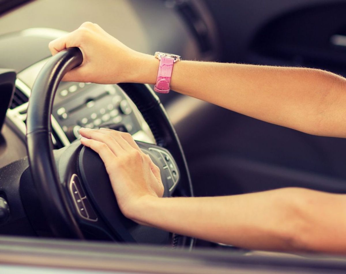transportation and vehicle concept – woman driving a car with hand on horn button
