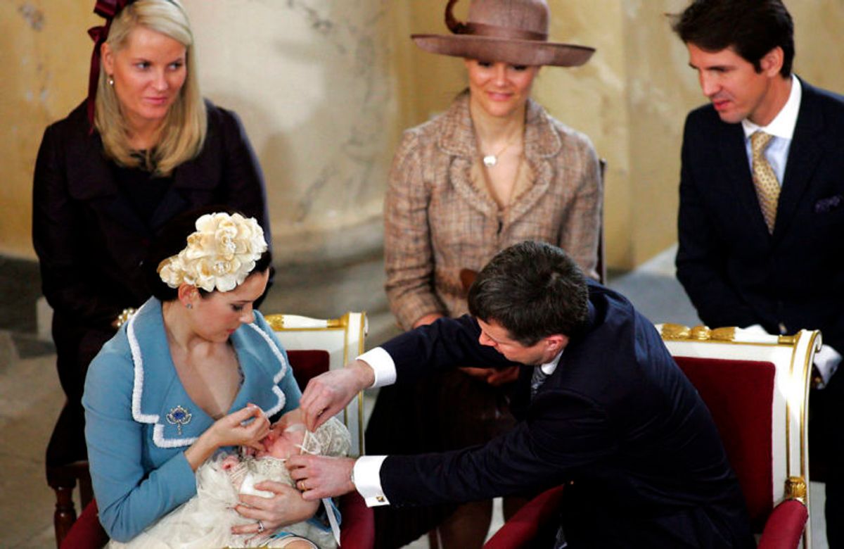 Prins Christian’ dåb i Christiansborg Slotskirke lørdag d. 21. januar 2006. Efter dåbshandlingen er det kronprins Frederik, der bakser med at få bundet sløjfen på den lille kyse, mens lille prins Christian Valdemar Henri John sutter på mors finger. Bagved ser tra af fadderne til, fra venstre, kronprinsesse Mette-Marit af Norge (tv), kronprinsesse Victoria af Sverige og kronprins Pavlos af Grækenland. Foto: Scanpix