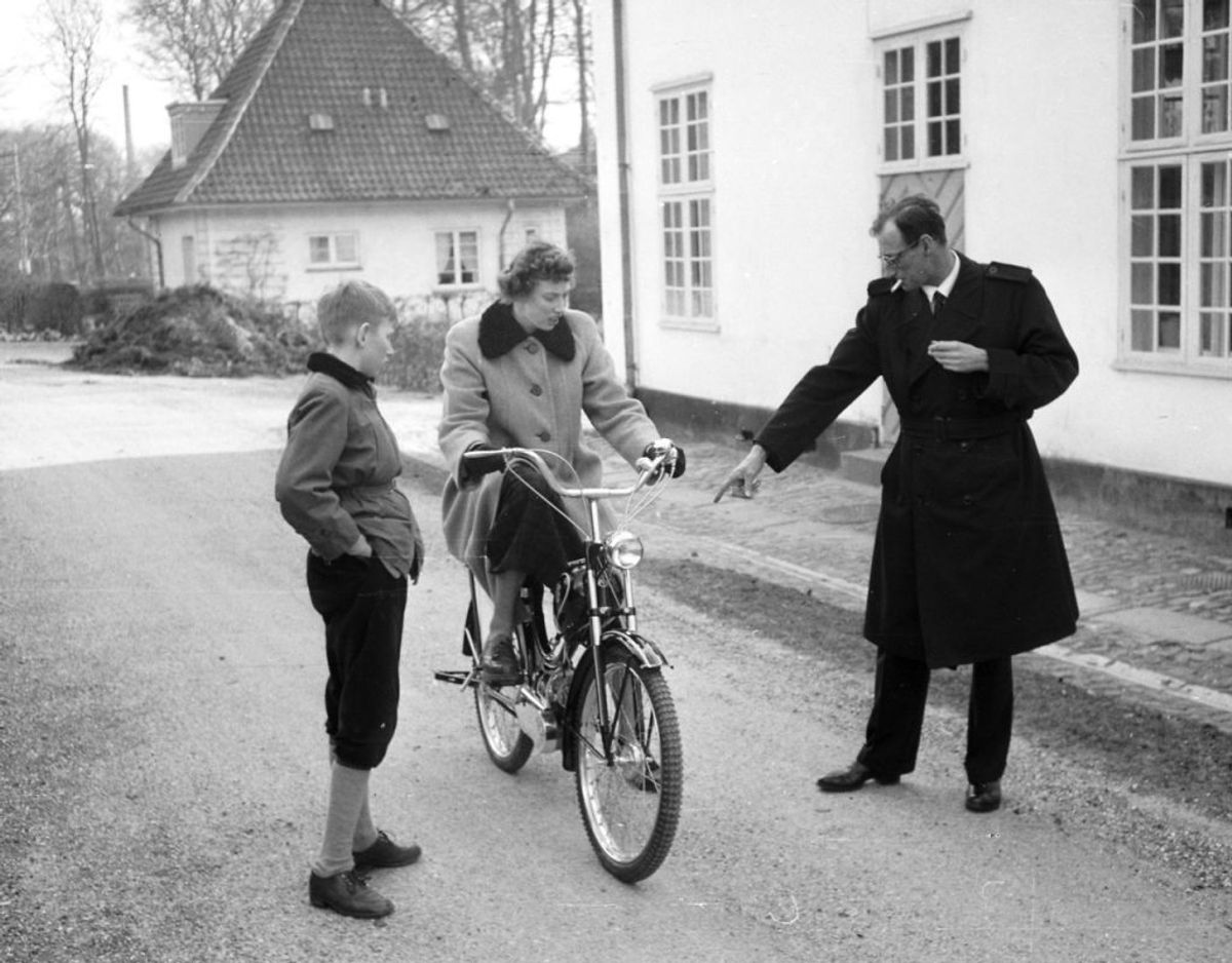 Ved Sorgenfri Slot prøver en ung prinsesse Elisabeth at køre på knallert, mens hendes bror prins Christian og faderen arveprins Knud ser på. Arkivfoto: Scanpix